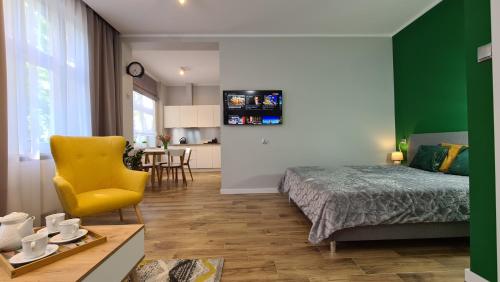 a bedroom with a bed and a yellow chair at Apartament Parkowy Studio in Gniezno
