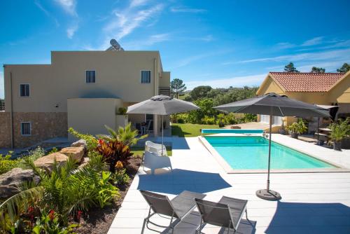 een zwembad met stoelen en parasols naast een huis bij Casa Gemeos in Alcobaça