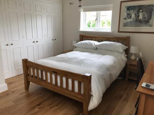 a bedroom with a bed with white sheets and a window at Lane End Cottage in Ovington