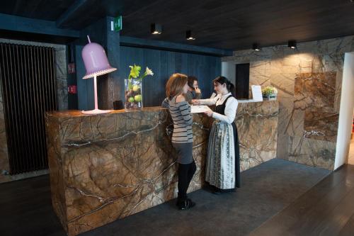 two women standing at a bar in a room at Alexander Charme Hotel in Livigno