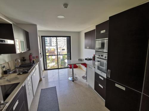 a kitchen with black cabinets and a large window at Sun Island Apartments in Funchal