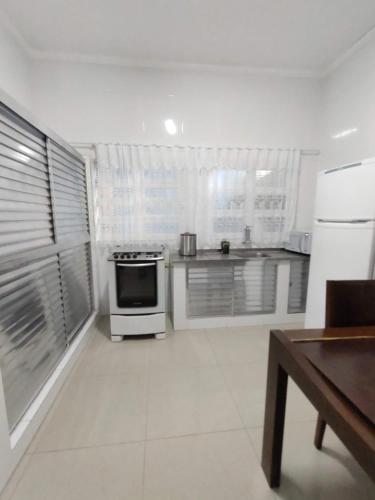 a white kitchen with a stove and a refrigerator at Pousada Vistazul - Pé na Areia in Bertioga
