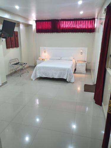 a bedroom with a white bed and a red curtain at HOTEL CENTRAL in Chiclayo