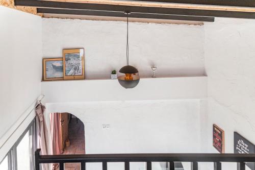 a room with white walls and a black pendant light at Olive View Loft in Dhíkella
