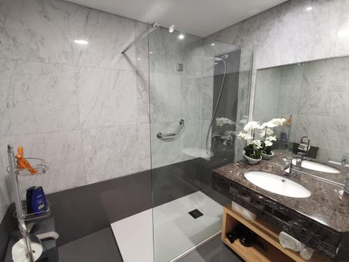 een badkamer met een wastafel en een glazen douche bij Sun Island Apartments in Funchal