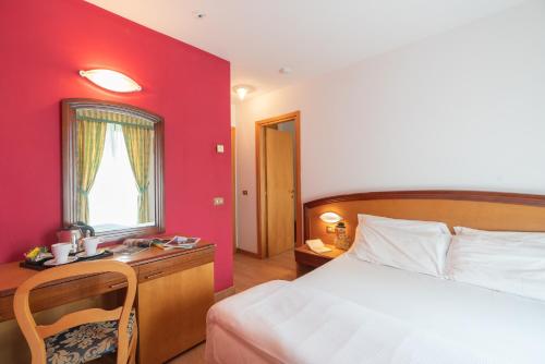 a bedroom with a bed and a red wall at Hotel Posta in Aprica