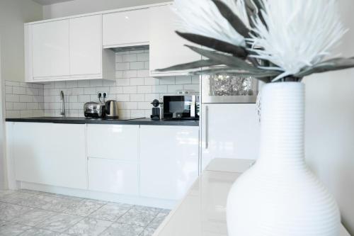 une cuisine blanche avec un vase et une plante. dans l'établissement 2-Bedroom Apartment Pointe Croisette Peaceful Walk to the Beach, à Cannes