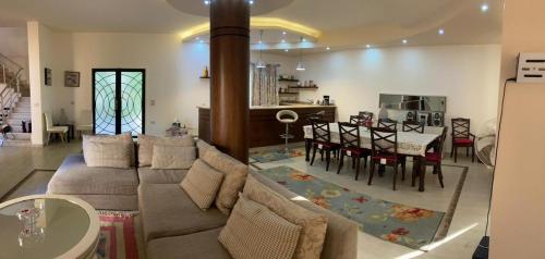 Relaxation Villa with private pool في الإسكندرية: غرفة معيشة مع أريكة وغرفة طعام