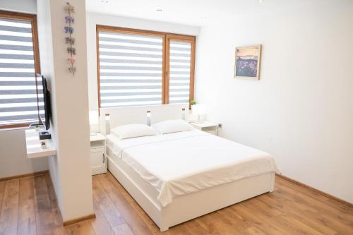 a white bedroom with a bed and a window at Shushi's Central Studio Apartment in Plovdiv
