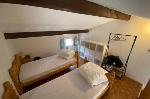 une petite chambre avec deux lits et une fenêtre dans l'établissement Maison saint cyprien plage, à Saint-Cyprien