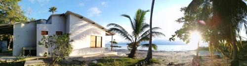 a white house on the beach with palm trees at La casa de la playa in Necoclí