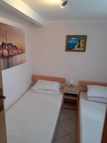 a room with two beds and a picture on the wall at Apartman Sanjković in Rovinjsko Selo