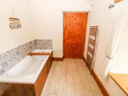 baño con bañera y puerta de madera en Cefn Werthyd Farmhouse, en Caernarfon