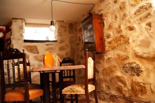 a room with chairs and a table and a stone wall at Quintinha Viçosa in Aldeia Viçosa