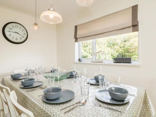a dining room with a table with a clock on the wall at Seaport Lodge in Mawgan Porth