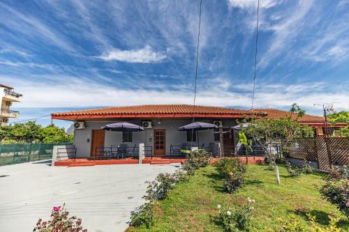 a house with purple umbrellas in front of it at Rose Garden Apartments in Mitikas