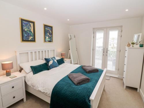 1 dormitorio con cama blanca y almohadas azules en Captain's Quarters - Apartment 2, en Benllech