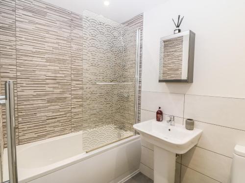 a bathroom with a shower and a sink and a tub at Captain's Quarters - Apartment 2 in Benllech