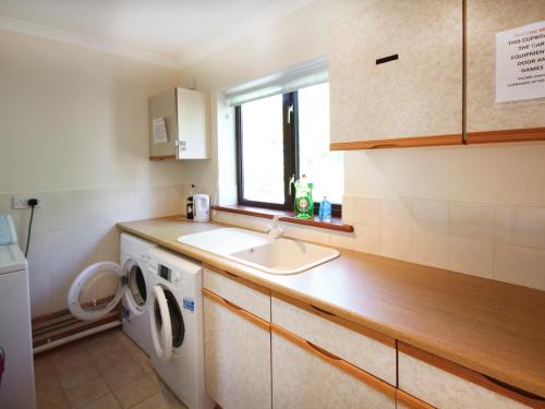 uma cozinha com um lavatório e uma máquina de lavar roupa em The Gables em Trearddur