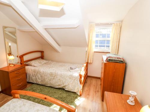 1 dormitorio con cama, escritorio y ventana en Stable 1 en Llanbedrog
