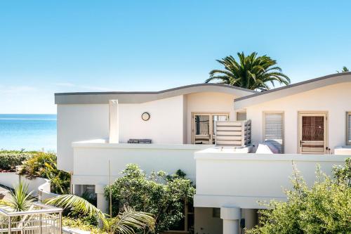 a white house with the ocean in the background at Onetangi Beach Apartments in Onetangi