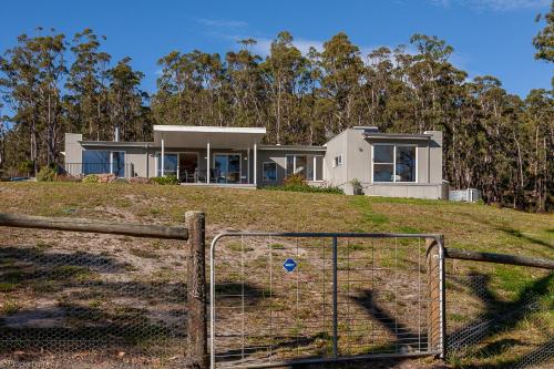 a house on top of a hill with a fence at Fairwinds Tasmania in Brooks Bay