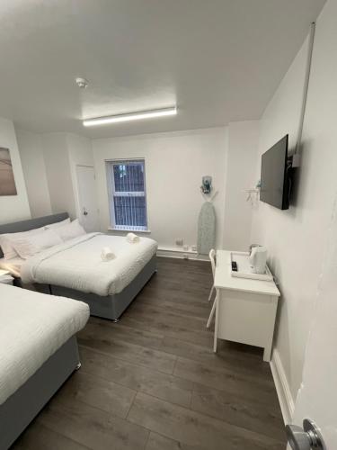 a room with two beds and a desk and a tv at County serviced accommodation in Liverpool