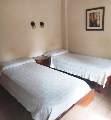 two beds in a room with white sheets at Hosteria Helvecia in Montecarlo