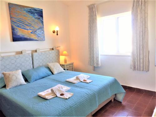 een slaapkamer met een blauw bed en handdoeken bij Favorite at Senhora da Rocha in Porches