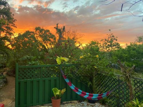 a hammock hanging on a fence at sunset at Judy House Cottages and Rooms in Negril