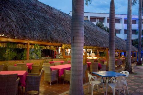 a restaurant with tables and chairs and palm trees at Hotel Bachue Girardot in Girardot