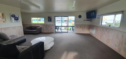 a living room with a couch and a table at Tasman Holiday Parks - Coromandel in Coromandel Town