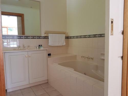 a white bathroom with a tub and a sink at Cradle Gateway Chalets in Moina