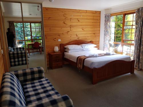a bedroom with a bed and a chair and a mirror at Cradle Gateway Chalets in Moina