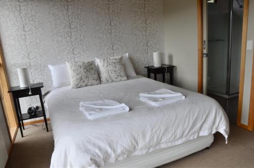 Un dormitorio con una cama blanca con toallas. en Schoren en Dinner Plain