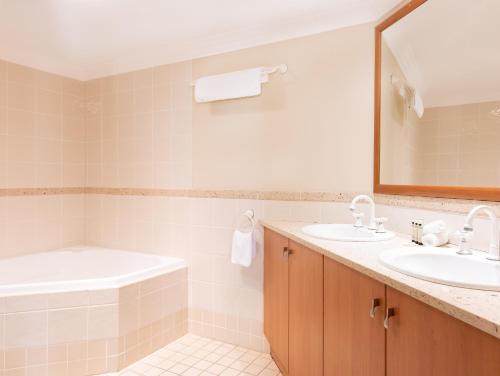 a bathroom with two sinks and a tub and a mirror at Breakers 1 10 LJHooker Yamba in Yamba