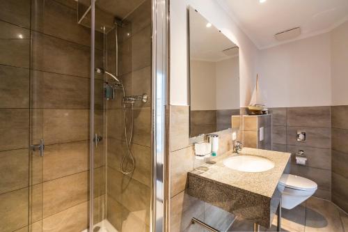 ein Bad mit einer Dusche, einem Waschbecken und einem WC in der Unterkunft Hotel Am Yachthafen in Waren (Müritz)
