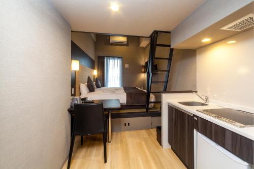 a bedroom with a bed and a desk with a sink at HOTEL SUITE HIROSHIMA YOKOGAWA in Hiroshima