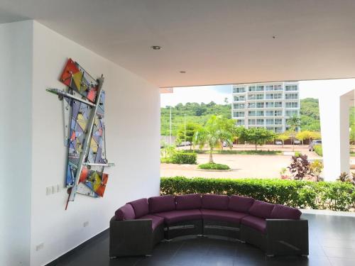 a living room with a purple couch and a large window at Departamentos frente al mar in Tonsupa