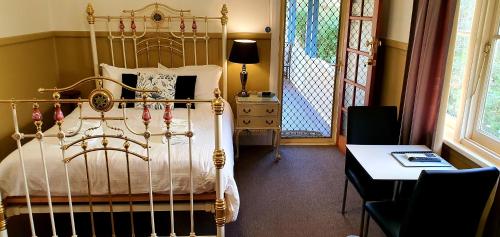 a bedroom with a gold bed with a table and a tableablish at Coppers Hill Private Accommodation in Gloucester