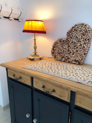 a lamp on a dresser with a heart on the wall at Manoir de Champvert in Les Vans