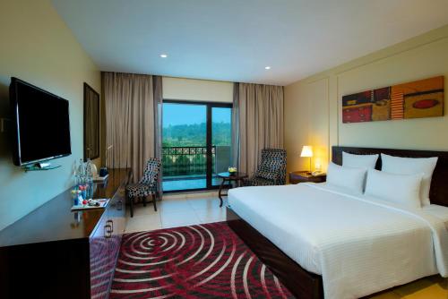 a hotel room with a large bed and a television at Novotel Imagicaa Khopoli in Khopoli