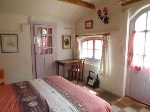 1 dormitorio con cama, mesa y ventanas en Chambre d'Hôtes Oeuil de Bouc, en Madiran