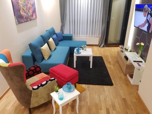 a living room with a blue couch and two chairs at SunStone Apartment in Zlatibor