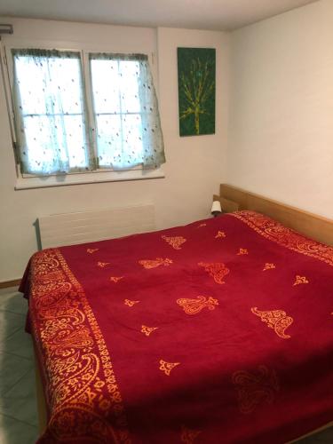 a red bed in a bedroom with two windows at Mona's Sleep & Go in Büren 