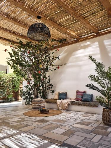 a patio with couches and a tree and a ceiling at Shellona Rooms & Apartments in Laganas