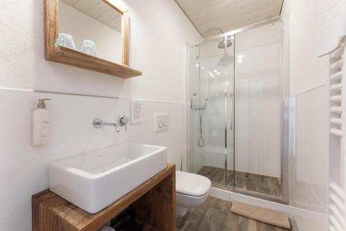 ein weißes Bad mit einem Waschbecken und einer Dusche in der Unterkunft Das Halali - dein kleines Hotel an der Zugspitze in Ehrwald