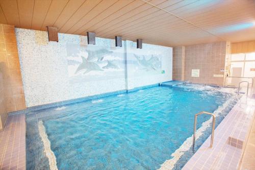a large swimming pool with blue water in a room at Kur and Hotel Isawa in Fuefuki