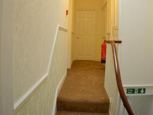 a hallway with a staircase with a red fire extinguisher at The Shrewsbury Guest House in Great Yarmouth