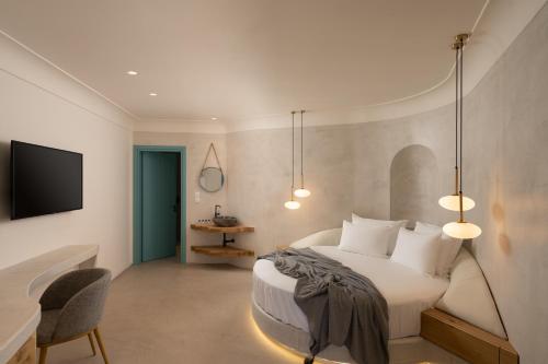 a bedroom with a bed and a tv and a chair at La Ponta Villas & Suites in Akrotiri
